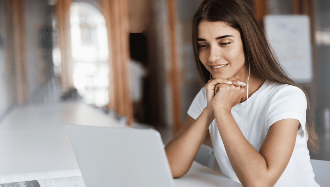 Mujer mira su blog en la pantalla de su notebook sentada en su escritorio